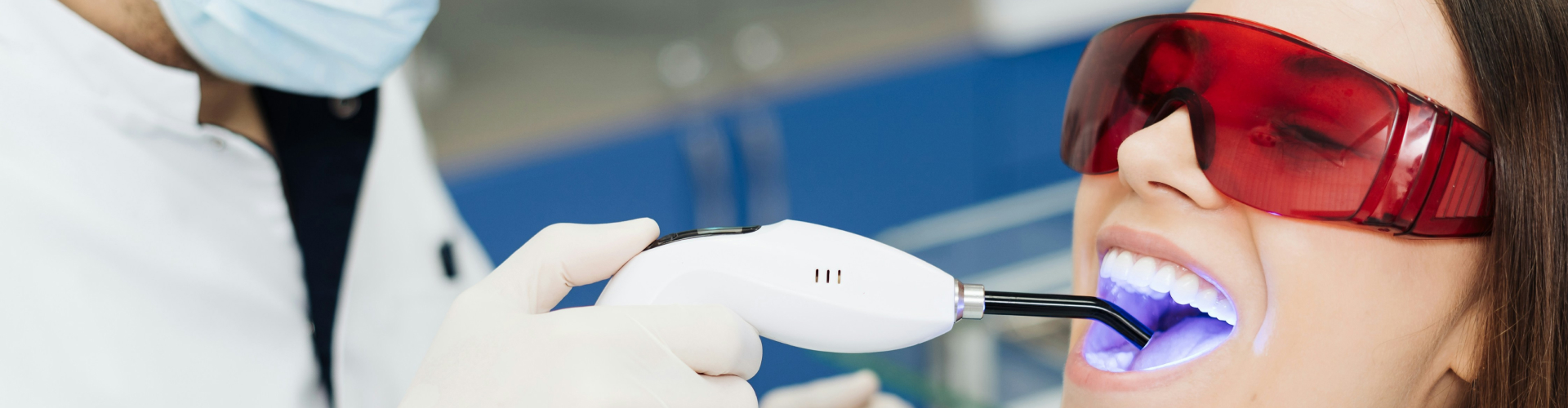 Gloved hand shining blue light on woman's smile.
